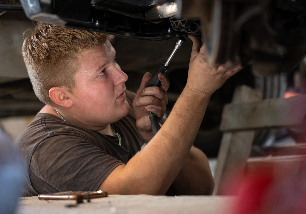 Photo of Young auto mechanic repairs a broken car in a car repair shop.